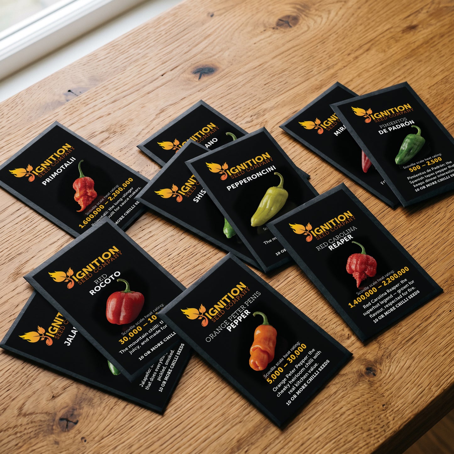 Ten black Ignition Seeds chilli seed packets spread across a wooden table